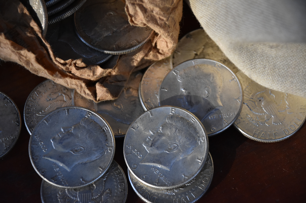 Vintage Kennedy half dollars spilling from a paper roll — Coin Buyers in Abilene.